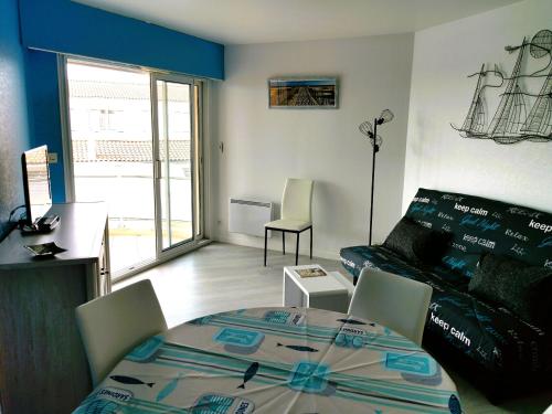 ein Wohnzimmer mit einem Tisch und einem Sofa in der Unterkunft Le Lagon Bleu in Les Sables-dʼOlonne