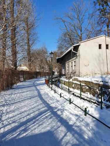 a snow covered street with a fence and a building at Apartamenty Magiczna Wenecja in Cieszyn