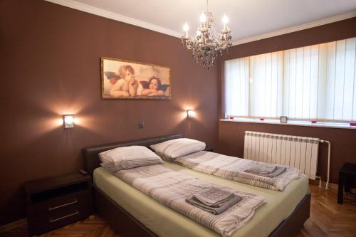 - une chambre avec un lit et un lustre dans l'établissement Angel Apartment, à Belgrade