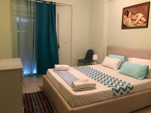 1 dormitorio con 1 cama grande y cortina azul en Genci Seaview Apartaments@AlbaResidence, en Sarandë