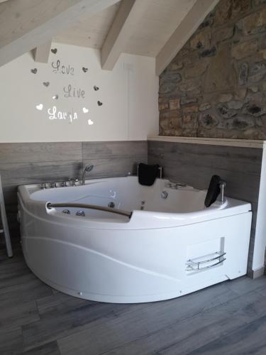una vasca bianca in un bagno con parete in pietra di White suite - Jacuzzi, Swimming pool & Lake view a Lezzeno