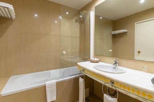 a bathroom with a tub and a sink and a mirror at Boa Vista Hotel & Spa - Adults Only in Albufeira