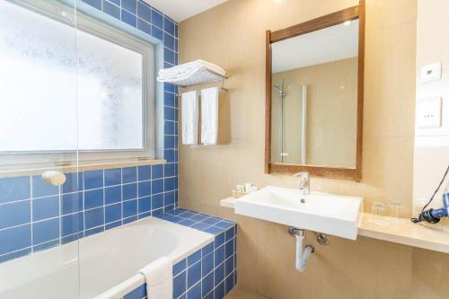a bathroom with a tub and a sink and a mirror at Boa Vista Hotel & Spa - Adults Only in Albufeira