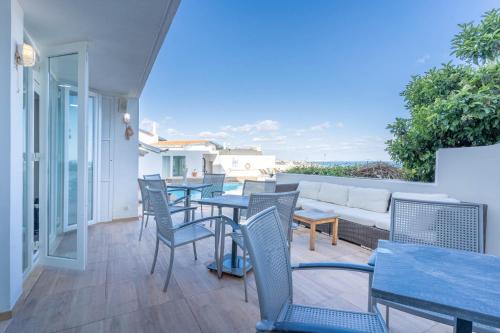 a patio with tables and chairs and a couch at Boa Vista Hotel & Spa - Adults Only in Albufeira
