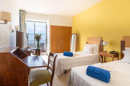 a hotel room with two beds and a desk and a window at Boa Vista Hotel & Spa - Adults Only in Albufeira
