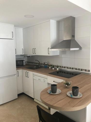 kuchnia z drewnianym stołem z dwoma kubkami w obiekcie Apartamento Maracena C/ Ramón y Cajal w mieście Maracena
