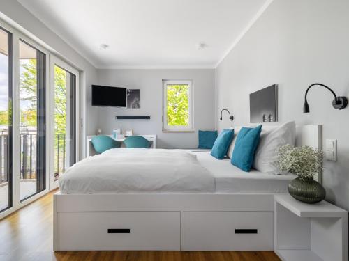 biała sypialnia z dużym łóżkiem z niebieskimi poduszkami w obiekcie numa I Munico Apartments w Monachium