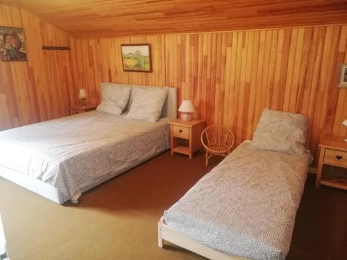 a bedroom with two beds in a room with wooden walls at 1.2.3 SOLEIL in Barcelonnette