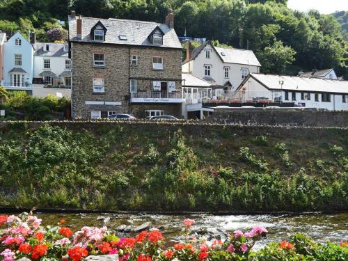 een groep huizen en een rivier met bloemen bij East Lyn House in Lynmouth