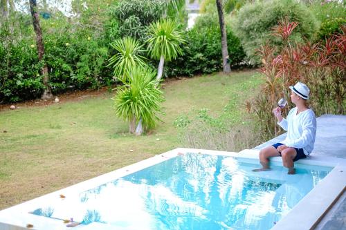 a man sitting on a ledge next to a swimming pool at Bungalow VILLA Rumba in Ko Yao Noi