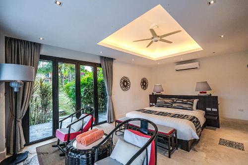a bedroom with a bed and chairs and a ceiling fan at Bungalow VILLA Rumba in Ko Yao Noi
