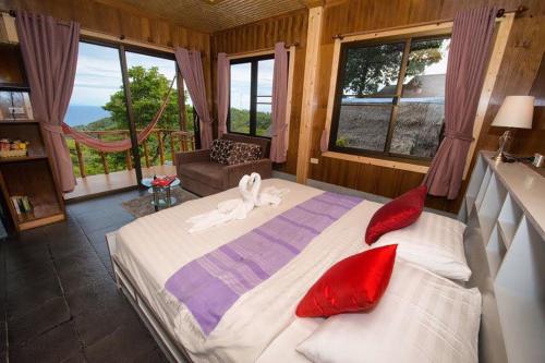 a bedroom with a large bed with red pillows at Tree House Bungalows Koh Tao in Koh Tao