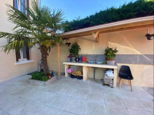 une terrasse avec une table et un palmier dans l'établissement Chambre Pinky Elisabeth proche Paris, à Stains