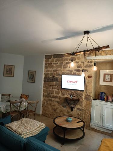 - un salon avec une télévision suspendue à un mur en briques dans l'établissement Maison de caractère au cœur de la cité médiévale de Gourdon, à Gourdon
