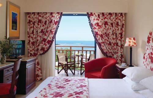 a hotel room with a bed and a balcony at Roda Beach Resort & Spa in Karousádes