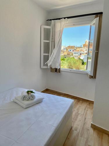 a white bedroom with a bed and a window at Cycladic Maisonette (Dryopida, Kythnos) in Kithnos