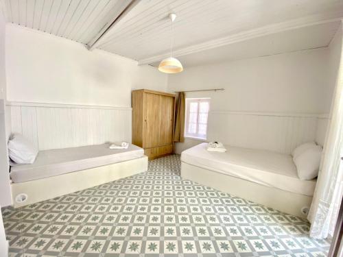 two beds in a room with a tiled floor at Cycladic Maisonette (Dryopida, Kythnos) in Kithnos