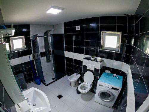 a black tiled bathroom with a toilet and a shower at Apartmani Đorđević in Soko Banja