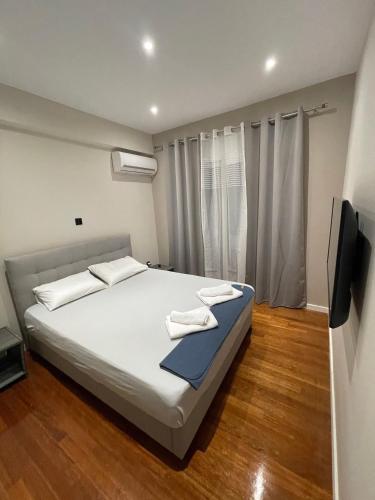 Schlafzimmer mit einem großen weißen Bett und einem Flachbild-TV in der Unterkunft Luxury 3 bedroom apartment in Kiato center in Kiato