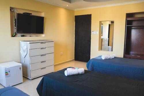 a bedroom with two beds and a tv and a dresser at Hotel Posada Las Lengas in Veintiocho de Noviembre