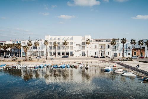 un grupo de barcos en una masa de agua con edificios en Hotel Falli en Porto Cesareo