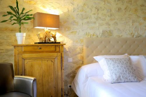 a bedroom with a bed with a lamp on a table at Maison CHENET - Les Chambres Entre Vigne et Garrigue - Teritoria in Pujaut