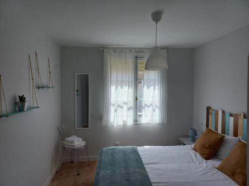 ein weißes Schlafzimmer mit einem Bett und einem Fenster in der Unterkunft Monte Sueve in Les Arriondes