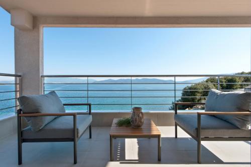 a balcony with two chairs and a table and a large window at Del Mare Suites in Glífa
