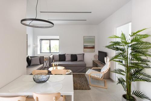sala de estar con sofá, mesa y palmera en Cozy Corner Luxury Apartments, en La Canea
