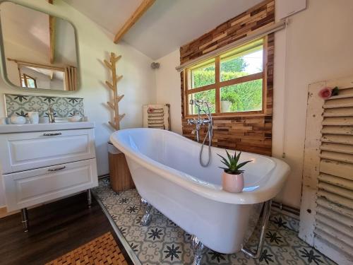 La salle de bains est pourvue d'une grande baignoire blanche et d'une fenêtre. dans l'établissement Chalet La Romance, à Prouilly