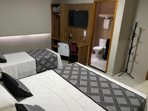 a hotel room with two beds and a television at VIPPER Hotel in Aparecida