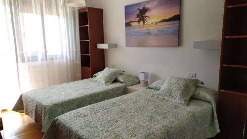 1 dormitorio con 2 camas y una foto en la pared en Ardan paraiso, en Pontevedra