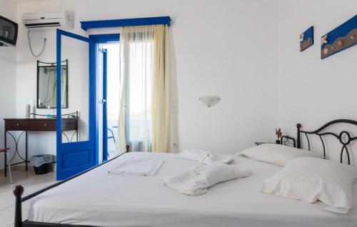 a bed with white sheets and a blue door at Vigles in Adamantas