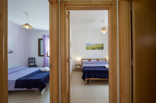 a room with two beds and a door to a bedroom at Staiulo - Primo Piano - La Plumeria in Leuca