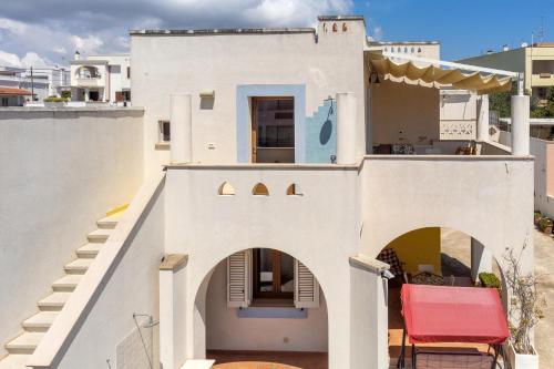 a white house with a red chair on the balcony at Staiulo - Primo Piano - La Plumeria in Leuca