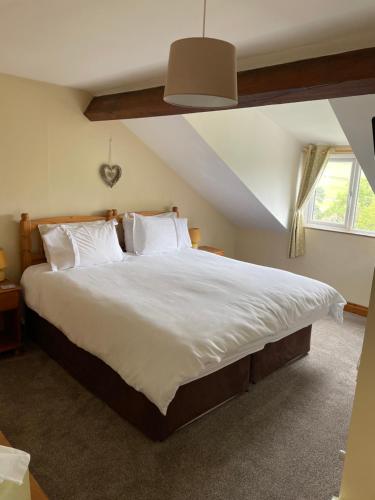 um quarto com uma cama grande com lençóis brancos e almofadas em Arkleside Country Guest House em Reeth