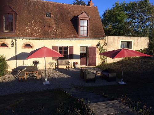 two red umbrellas in front of a building at Cottage du vigneron in Vernou-sur-Brenne