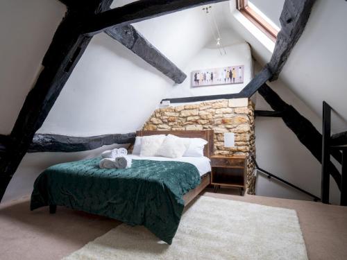 a bedroom with a bed and a stone wall at Pass the Keys Charming 18th Century 4 bedroom cottage in Moreton in Marsh