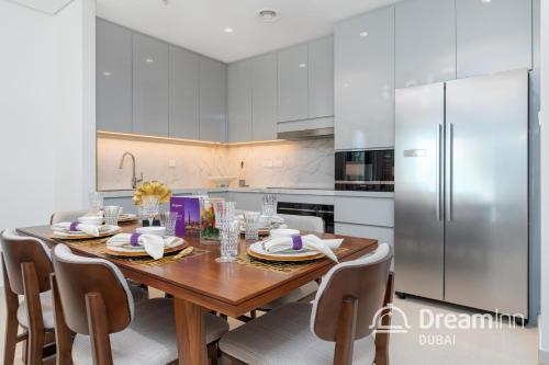 a kitchen with a wooden table and a stainless steel refrigerator at Dream Inn Apartments - Address Beach Residence Fujairah in Fujairah