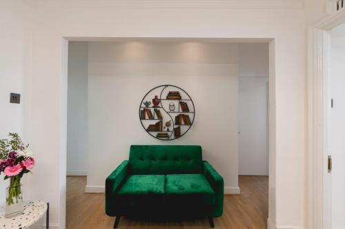 a green couch in a living room with a mirror at **Authentic & Spacious 5 Bed Apartment/Hyde Park** in London