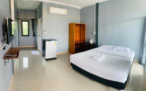 um quarto com uma cama branca e uma televisão em บ้านพิชชา ที่พักใจกลางเมืองปราณบุรี em Ban Khao Noi