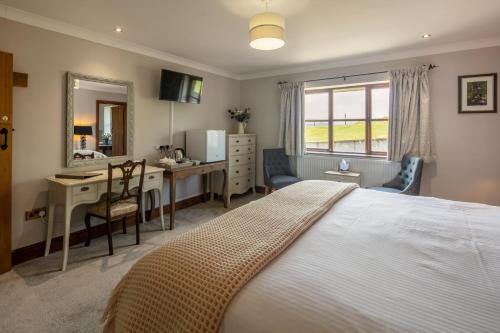 um quarto com uma cama, uma secretária e um espelho em Beaconsview B&B em Brecon