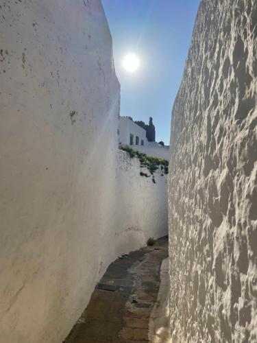an alley in a wall with the sun in the background at Patmos Horizon in Patmos