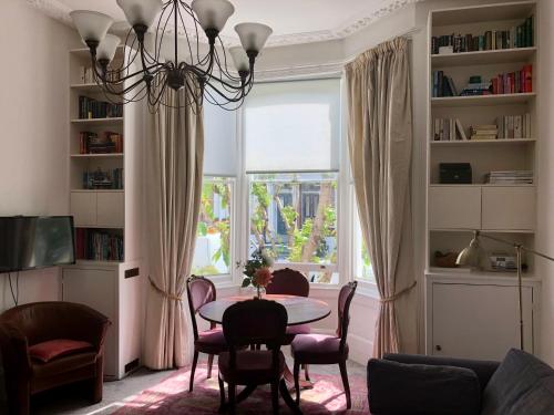 sala de estar con mesa, sillas y ventana en Olympia W14 Two-Bedroom Apartment en Londres
