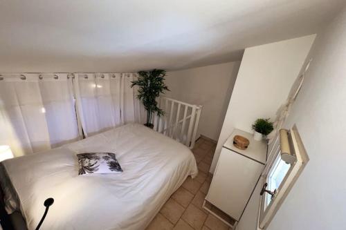 Un dormitorio pequeño con una cama blanca y una planta. en La TOUR DES TEINTURIERS - AC CLIM - WiFi - BALCON, en Aviñón
