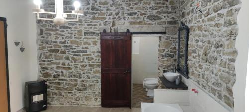 baño con pared de piedra y puerta de madera en Il Panorama Housing Cilento, en Santa Maria di Castellabate