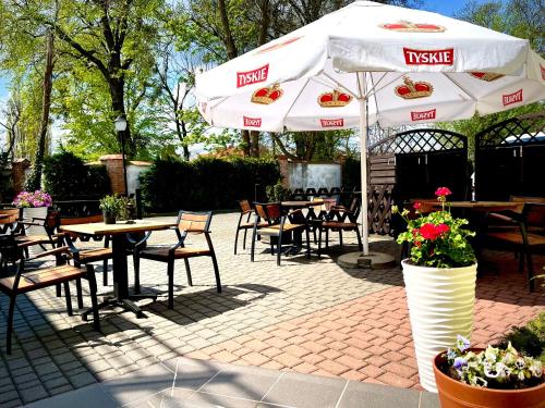 a patio with tables and chairs and an umbrella at Hotel Dowhań in Nowe