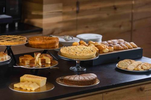 a table with different types of cakes and pastries at Residence Adamello Resort in Ponte di Legno
