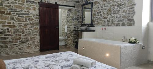 a bathroom with a bath tub and a stone wall at Il Panorama Housing Cilento in Santa Maria di Castellabate
