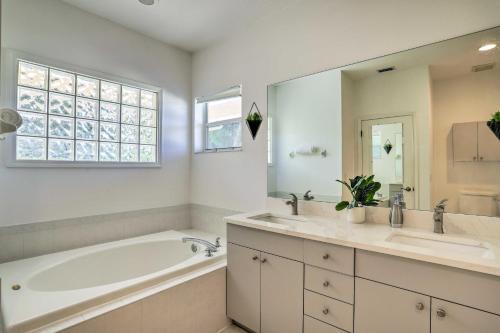 a white bathroom with a tub and a sink and a tubermott at Modern Clearwater Home with Deck 9 Mi to Beach in Clearwater